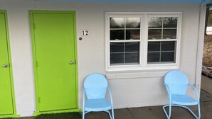 A house with a green door, a window, and two blue chairs outside. - Yellow Springs Motel (Yellow Springs)