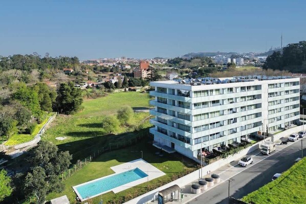 A modern hotel with a rooftop pool and a view of the surrounding area.