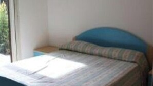 Een slaapkamer met een bed, een plafondventilator, een raam en uitzicht op groen.