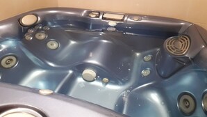 Ein blauer Whirlpool mit Bedienelementen und einem Ablauf.