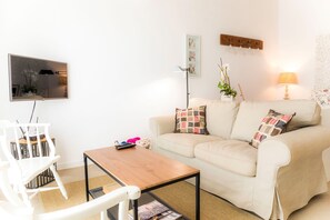 Una sala de estar con un sofá, una mesa de centro, un televisor y una lámpara.