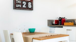 A dining area with a wooden table, white chairs, and a wall clock.