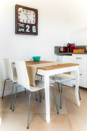 Un comedor con una mesa de madera, sillas blancas y un reloj de pared.