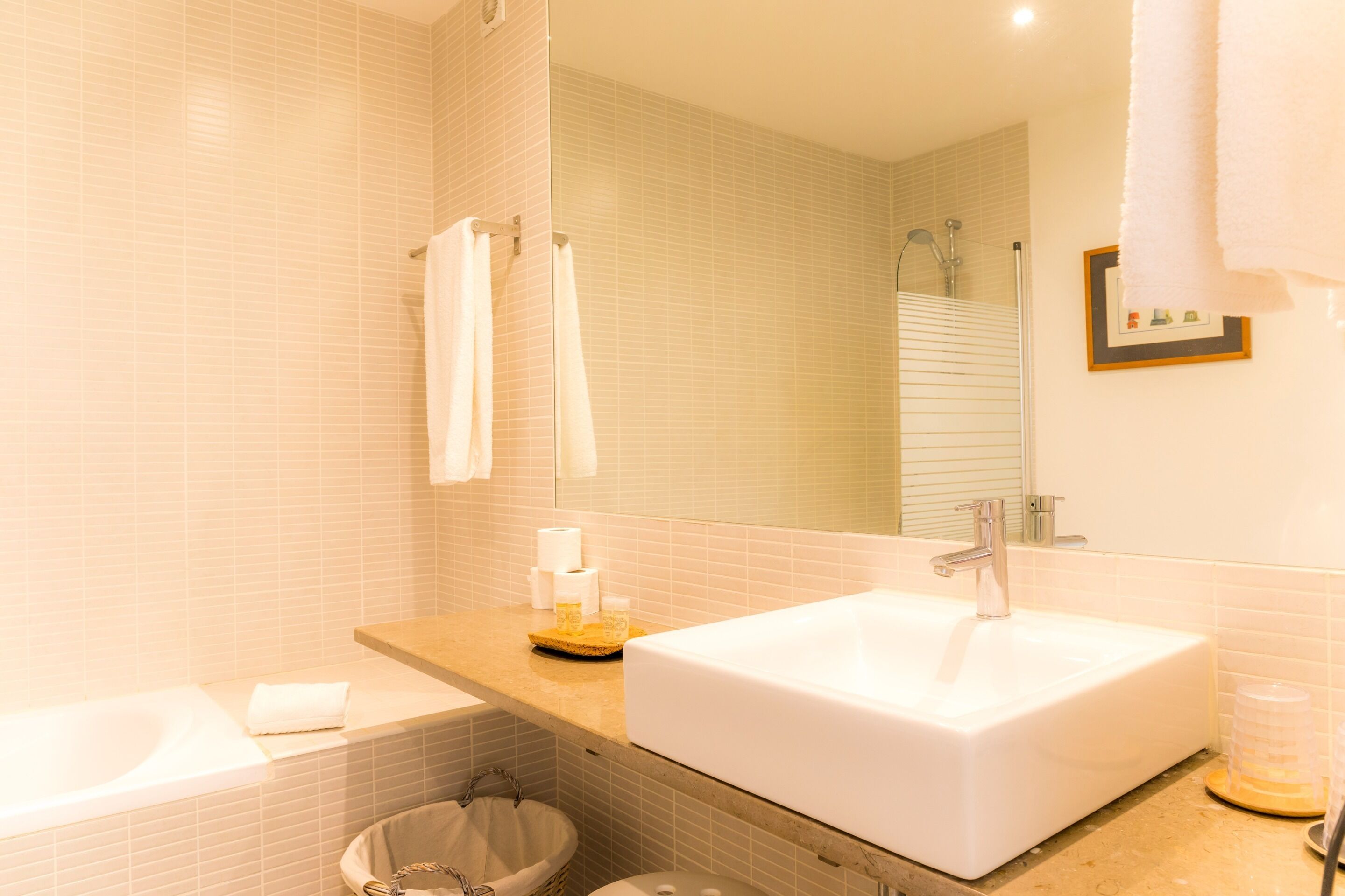 Un bagno con un lavandino bianco, uno specchio e un portascopevoli.