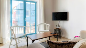 A room with a blue door, white chairs, a TV, and a small table.