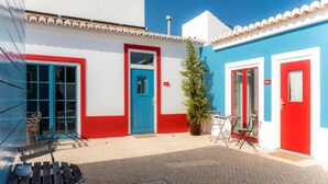 A building with a red and white facade, a blue door, and a small potted plant in the center.