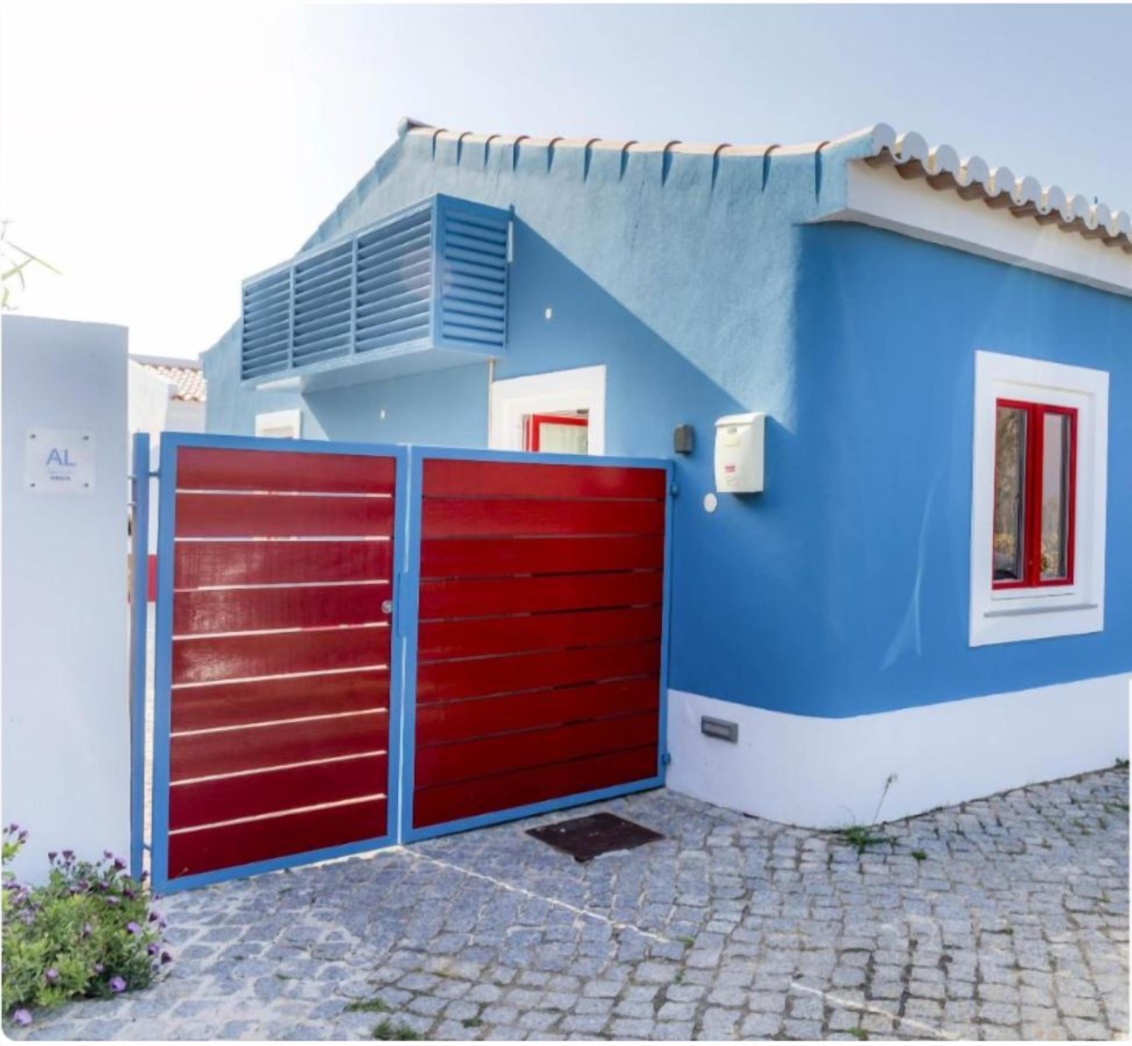 A blue building with a red garage door, a tiled roof, and a sign indicating 'Clean & Safe' tourism in Portugal.