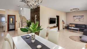 A modern living room with a dining area, a staircase, a TV, and a sofa. - Aileen Villa with Private Pool (Κοσκινού)