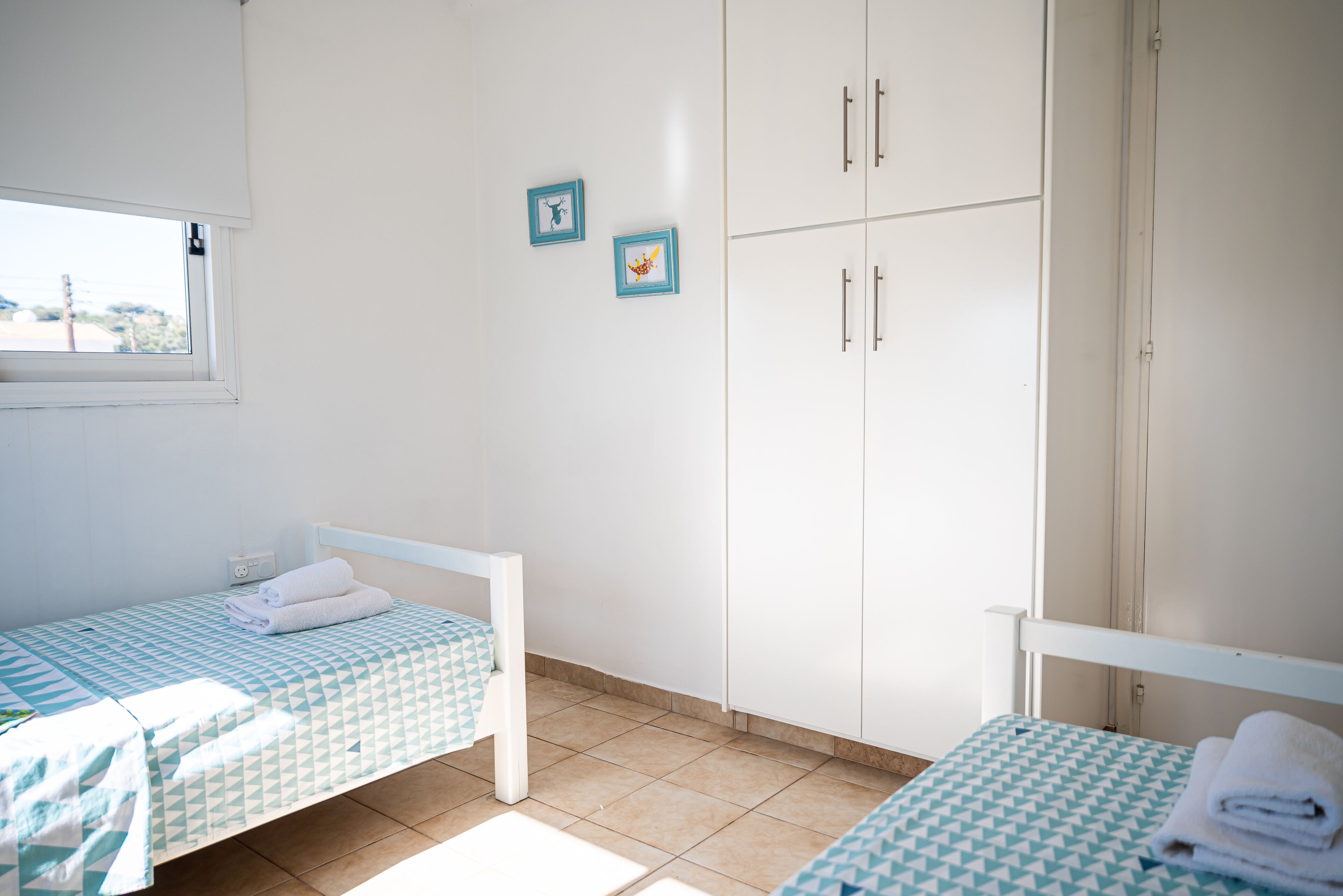 A bedroom with two single beds, a wardrobe, and a window.