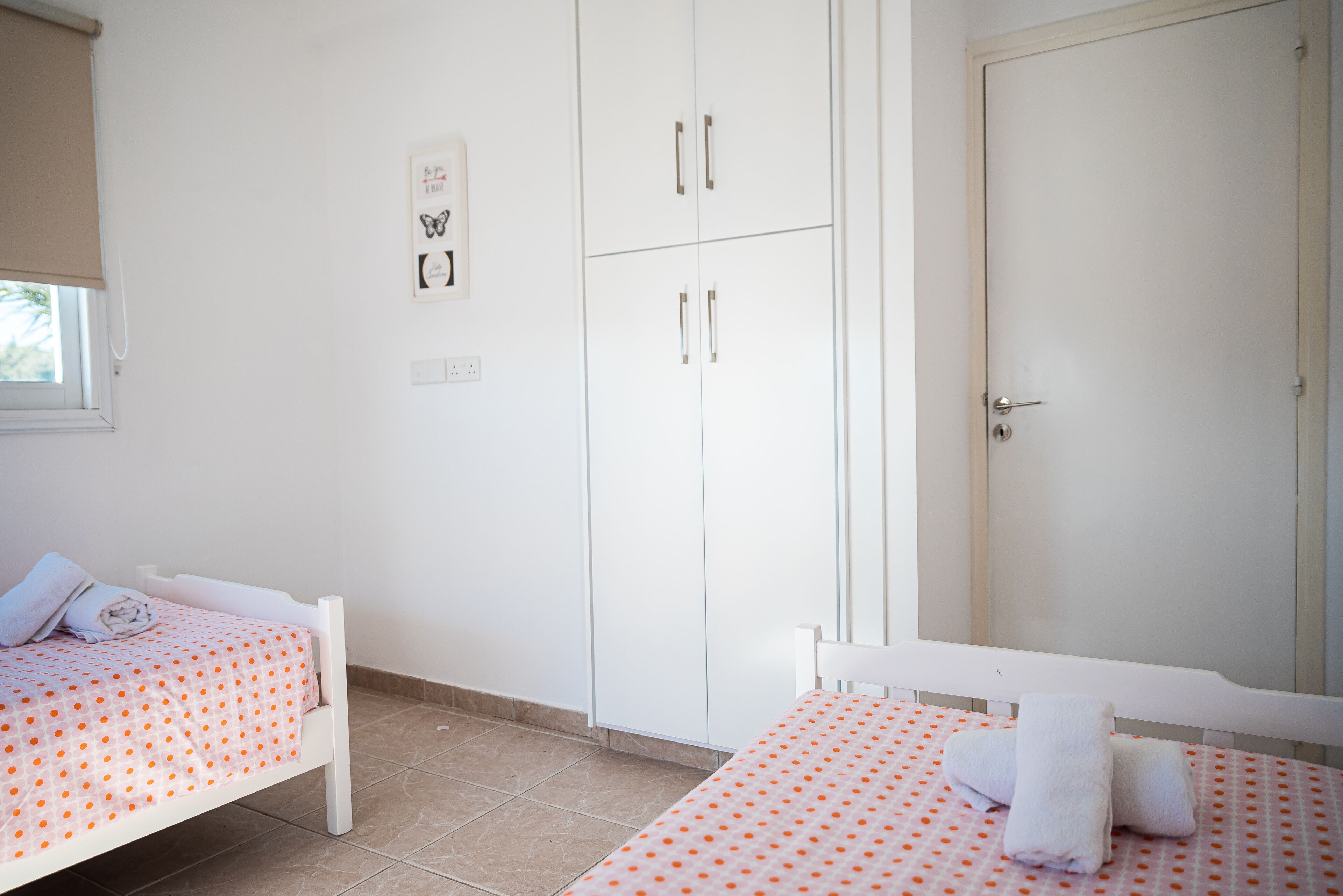 Un dormitorio con dos camas individuales, un armario y la puerta de un baño.