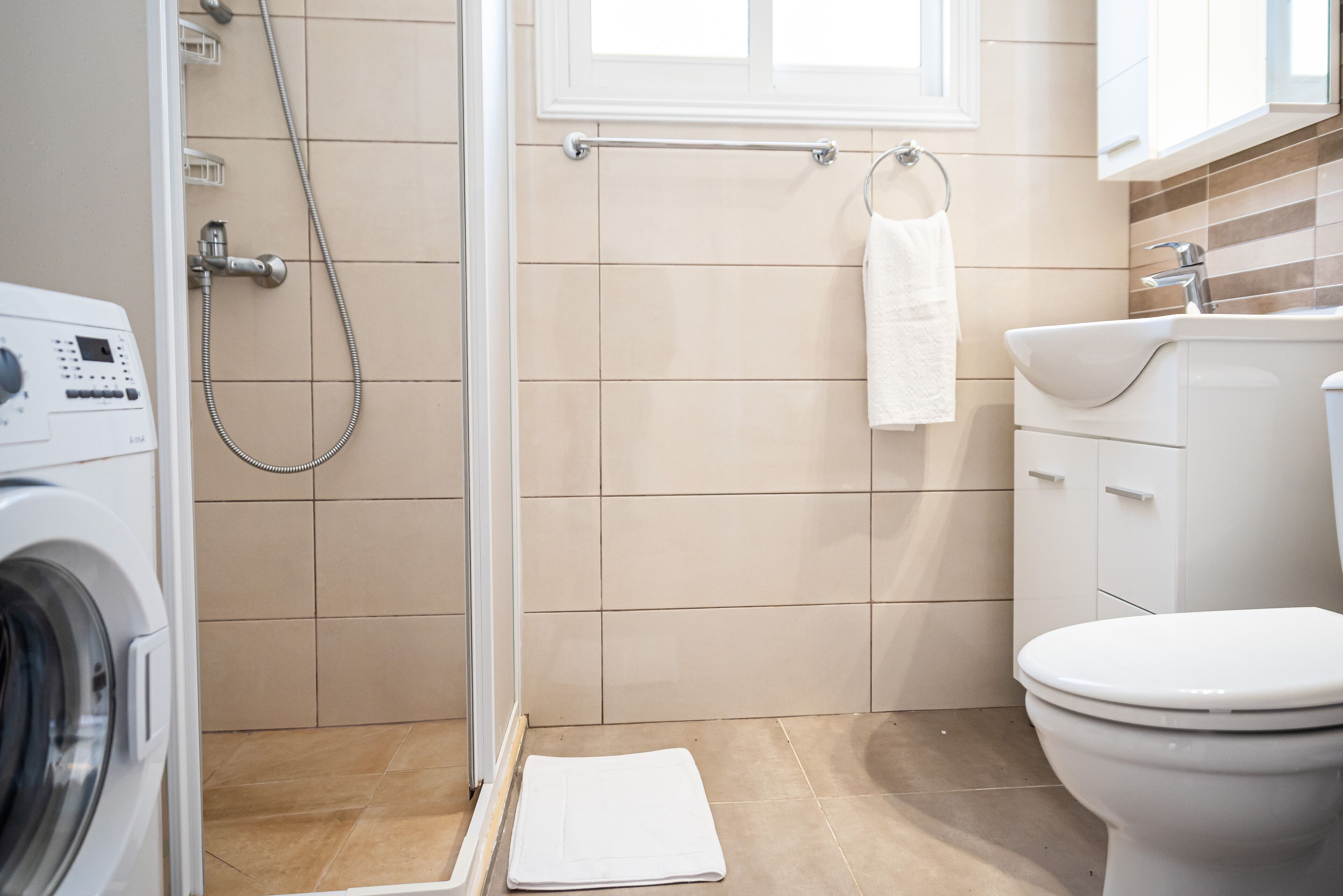 Kylpyhuone, jossa on pesukone, suihku, wc ja pesuallas.