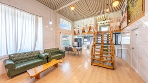 A spacious living area with a green sofa, wooden coffee table, and a wooden spiral staircase. - Gapyeong Ddel Poolvilla (Gapyeong)