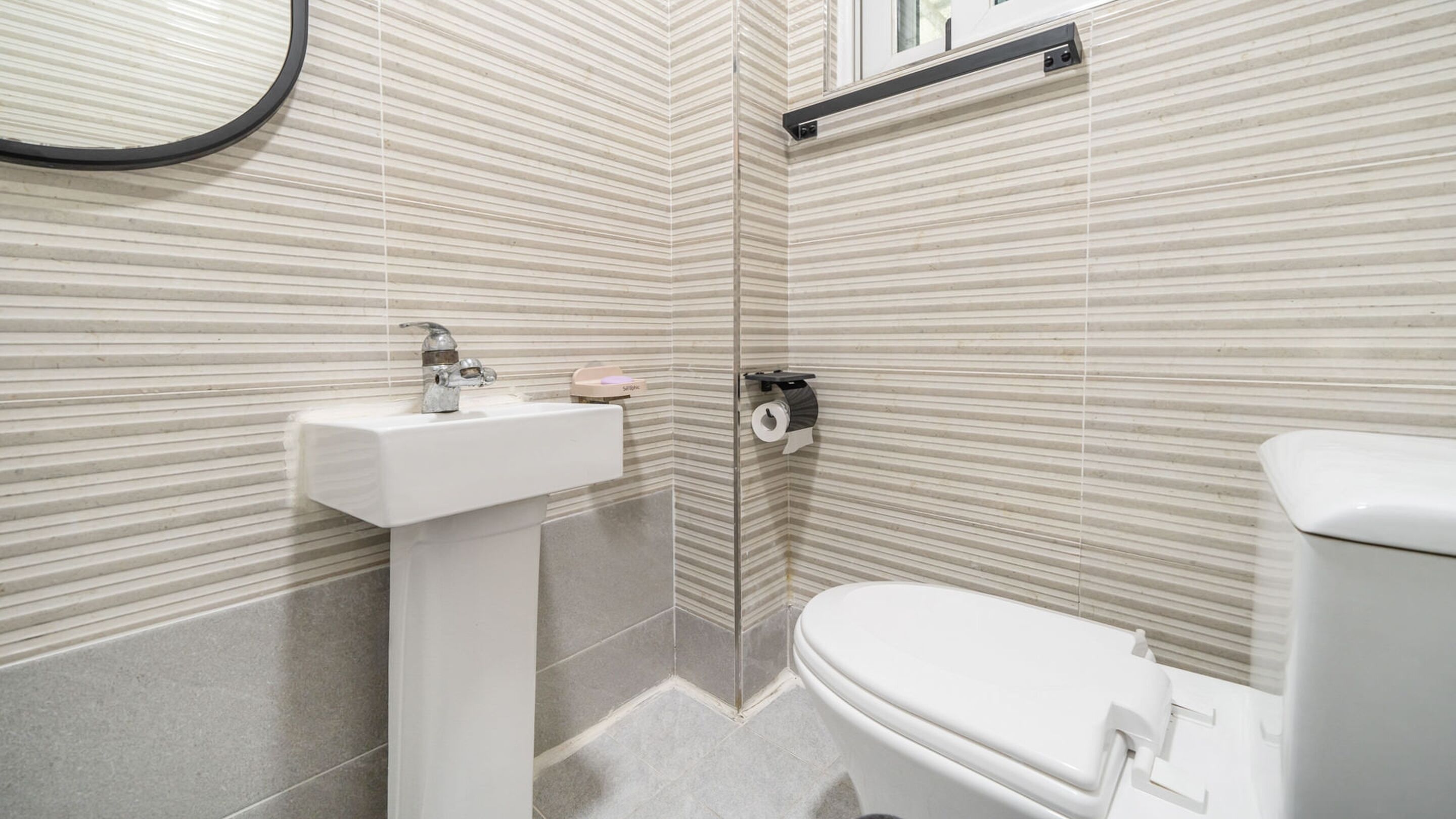A bathroom with a white sink, toilet, and a towel rack.