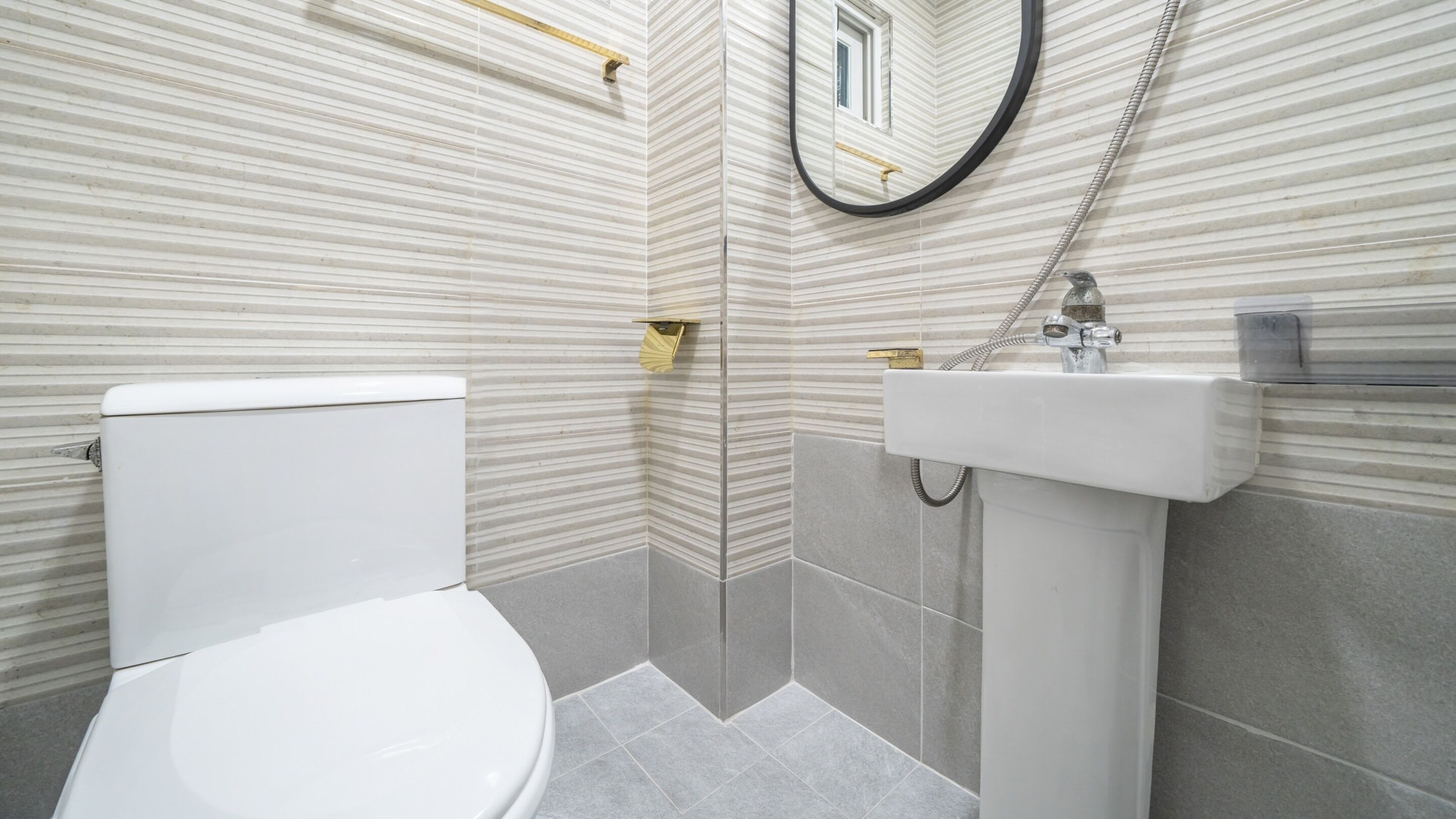 A modern bathroom with a white toilet, a sink, and a shower.