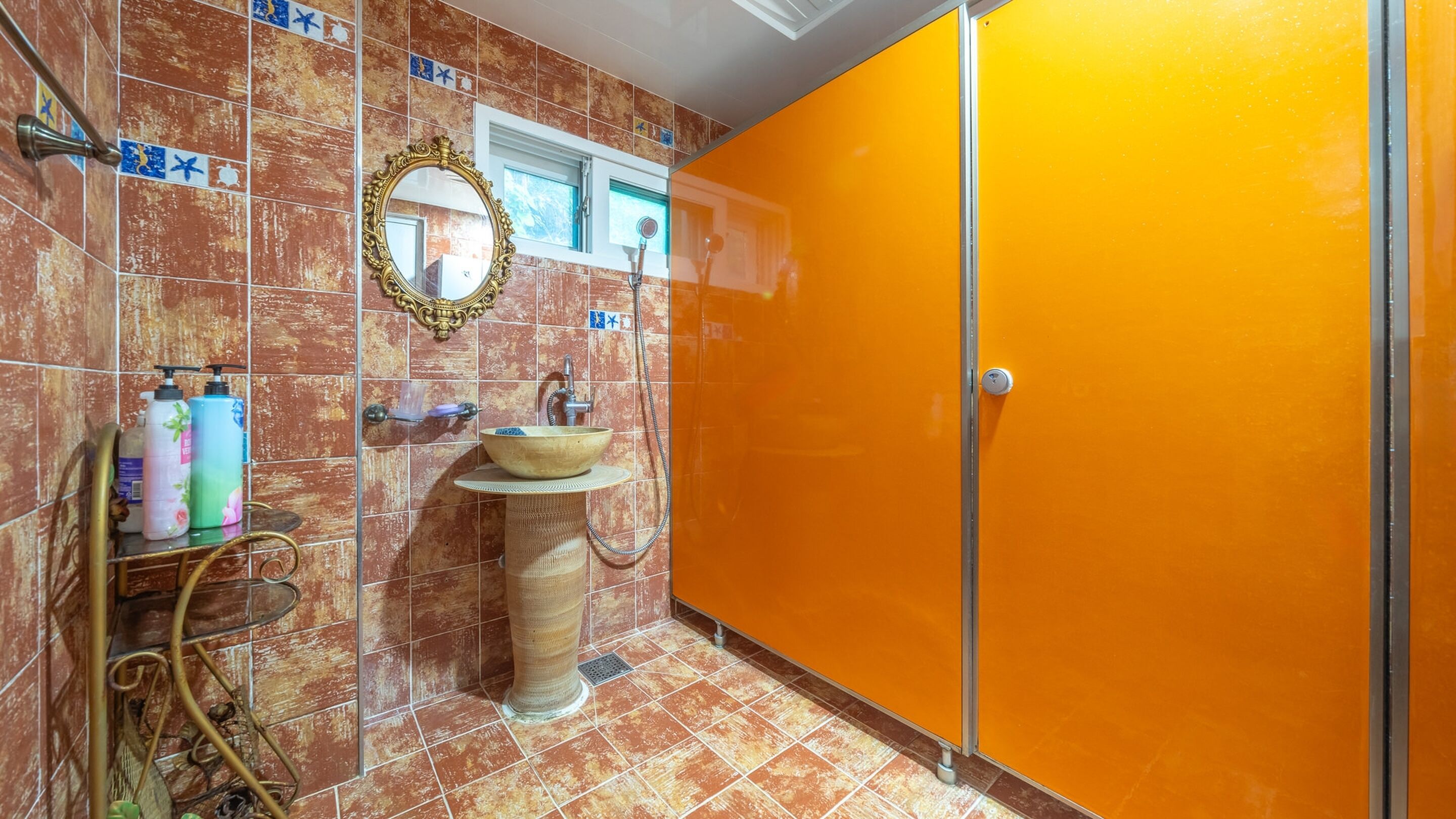 A bathroom with a sink, mirror, and orange cabinet.