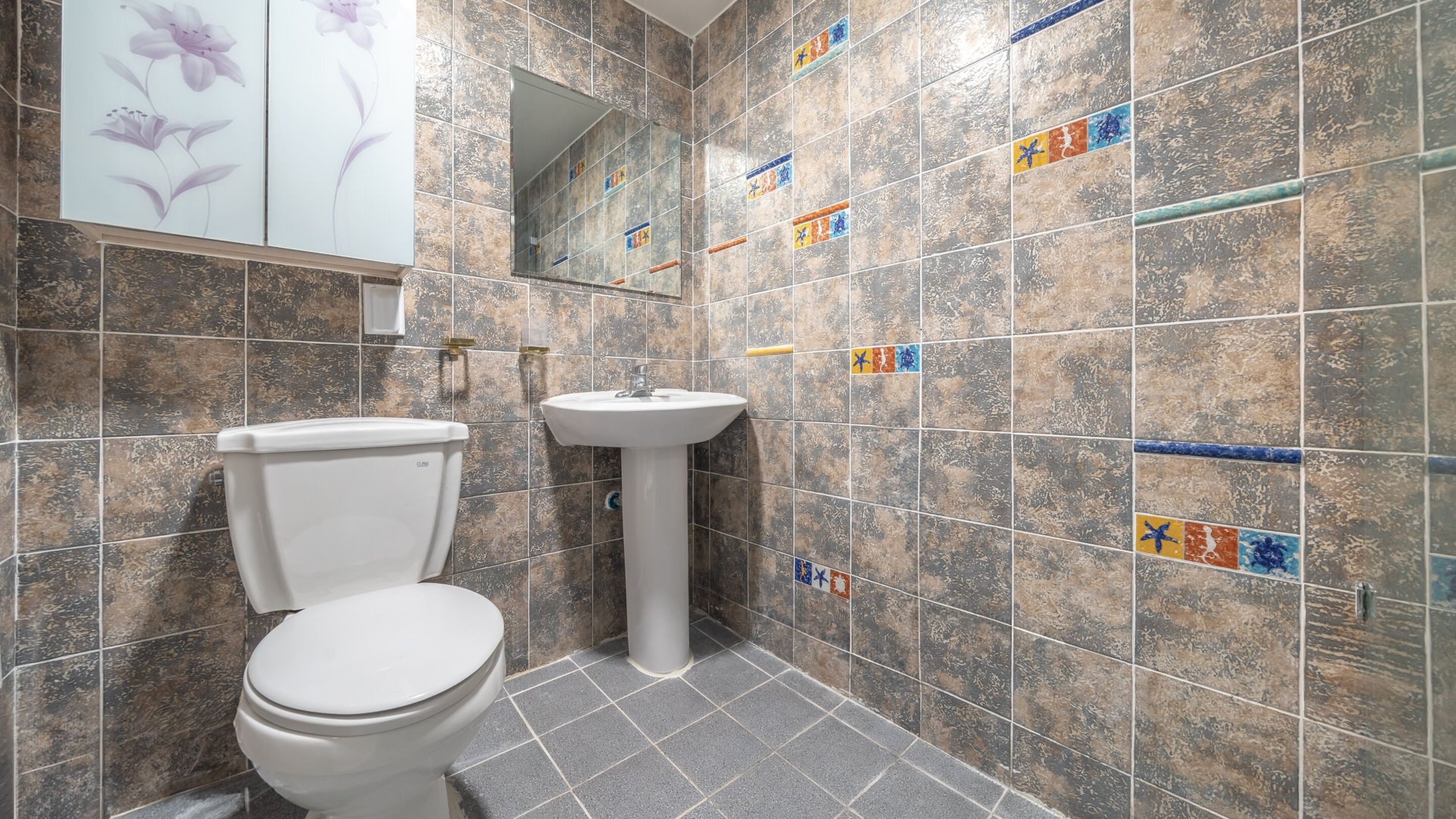 A bathroom with a toilet, a sink, and tiled walls.