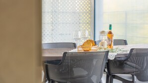 A dining table set with wicker chairs, a candle, a bottle, and bread. - Gapyeong Ddel Poolvilla (Gapyeong)