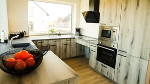 Et moderne køkken med et stort vindue, træskabe, en mikroovn og en kaffemaskine.