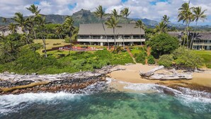 Ein Strandhotel mit klarem Meerwasser, Palmen und einer bergigen Kulisse.