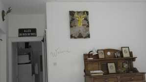 Une pièce avec une commode en bois, des tableaux encadrés et un panneau fixé au mur.