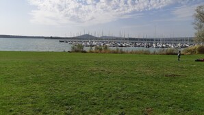 Un port de plaisance avec des bateaux amarrés, une zone herbeuse au premier plan et un ciel dégagé avec des nuages.