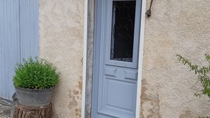 Une porte avec une fenêtre, un pot de fleurs et un tronc d’arbre.