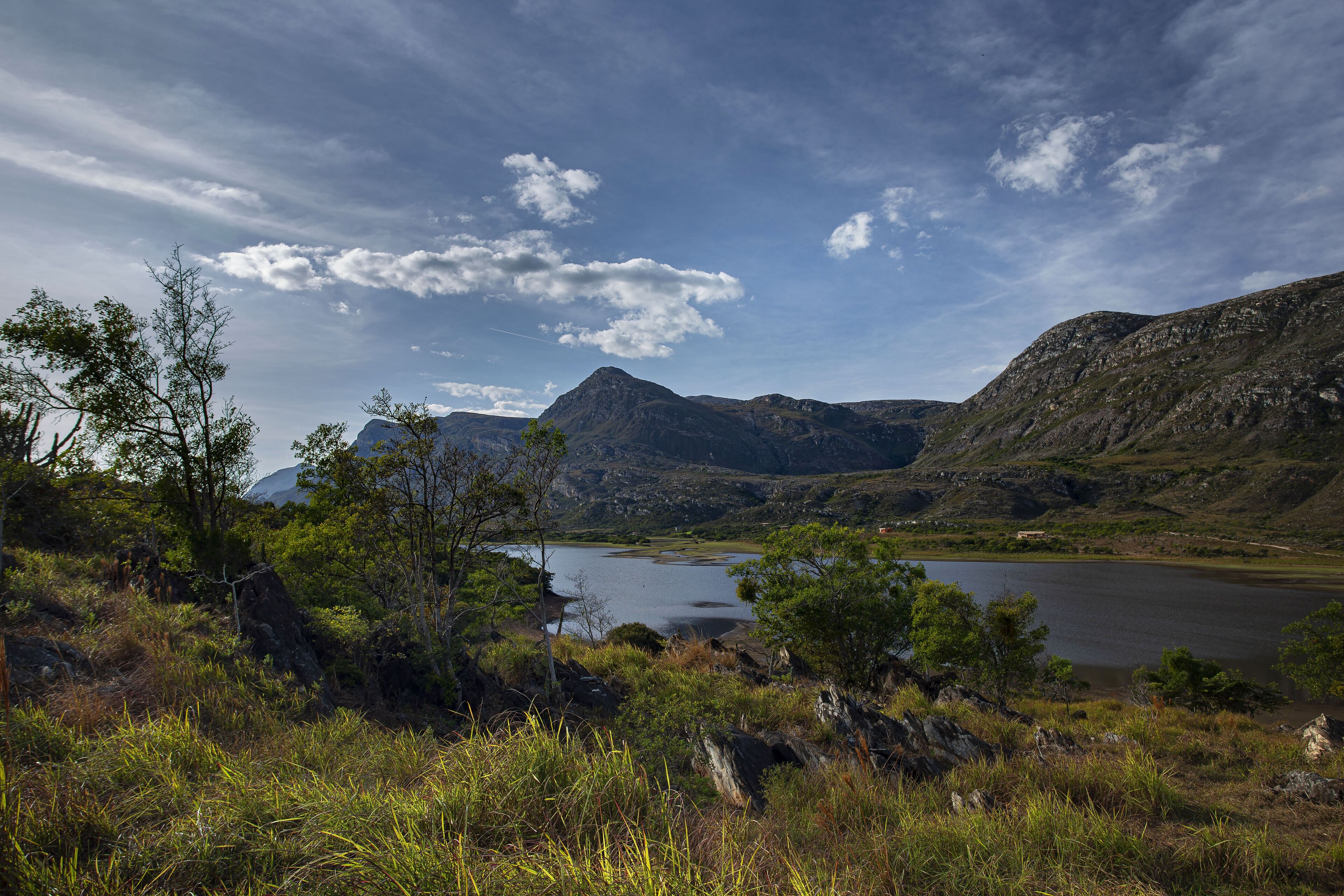 Un paisaje montañoso con un lago, rodeado de vegetación y terreno rocoso.