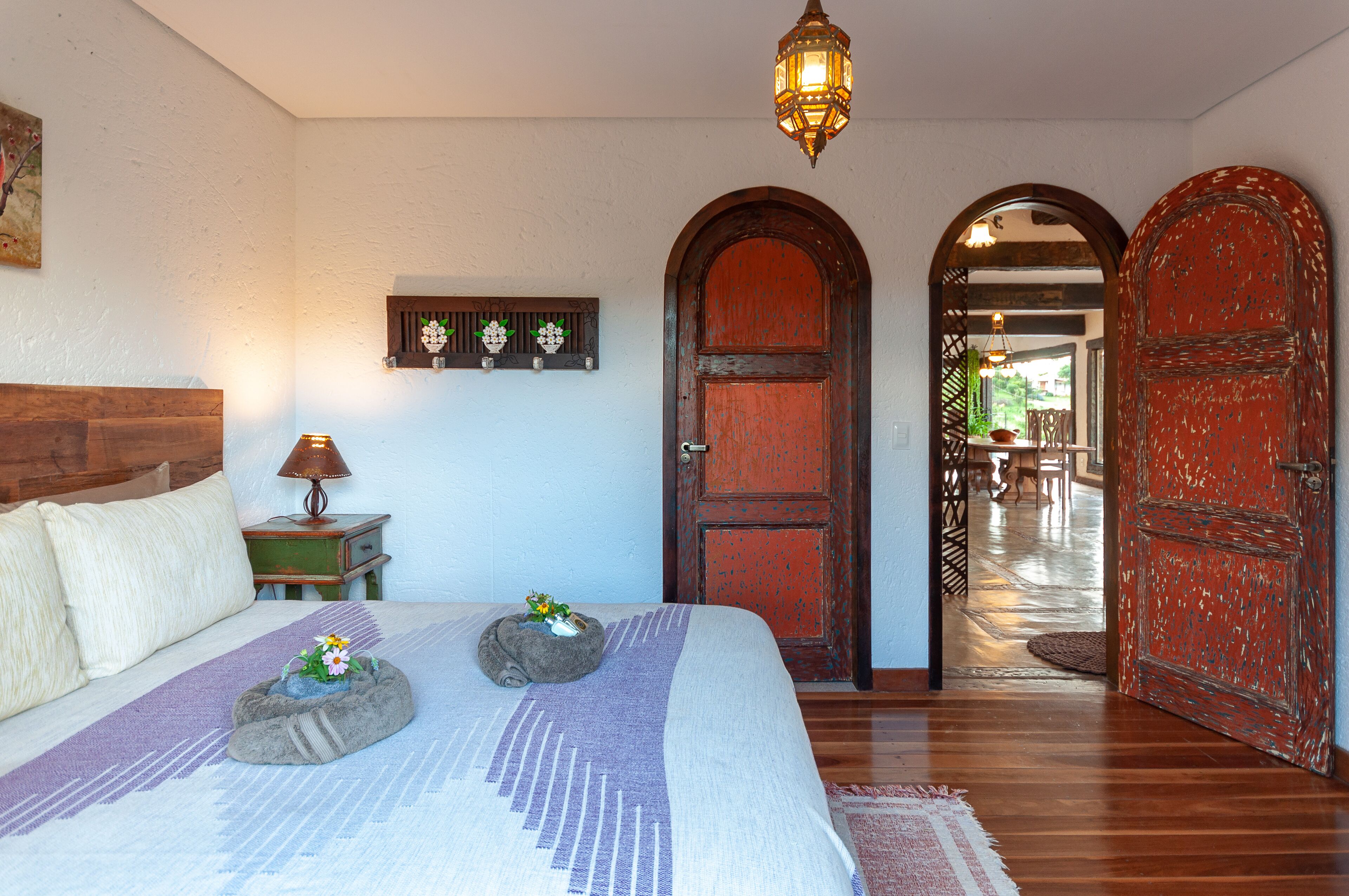 A bedroom with a bed, a nightstand, a lamp, and a decorative wall piece.