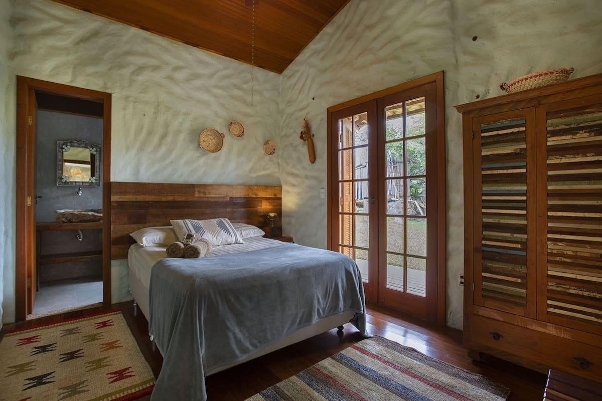 Une chambre avec un lit en bois, une grande fenêtre et un décor mural rustique.