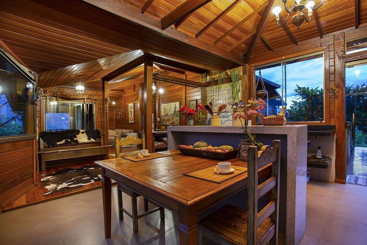 Un intérieur chaleureux et rustique, avec des poutres en bois et un coin repas comprenant une table et des bancs en bois.