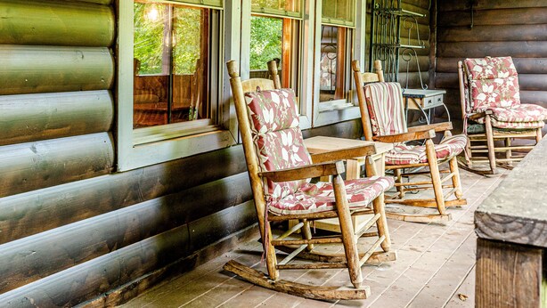 Eine Blockhütte mit Veranda, ausgestattet mit Schaukelstühlen und einem Tisch.