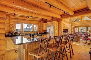 A spacious log cabin interior with a large kitchen, dining area, and a cozy living room.