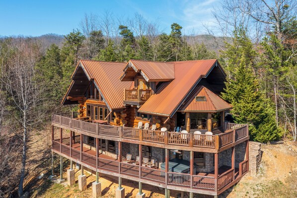A multi-level wooden cabin with a balcony, surrounded by trees.