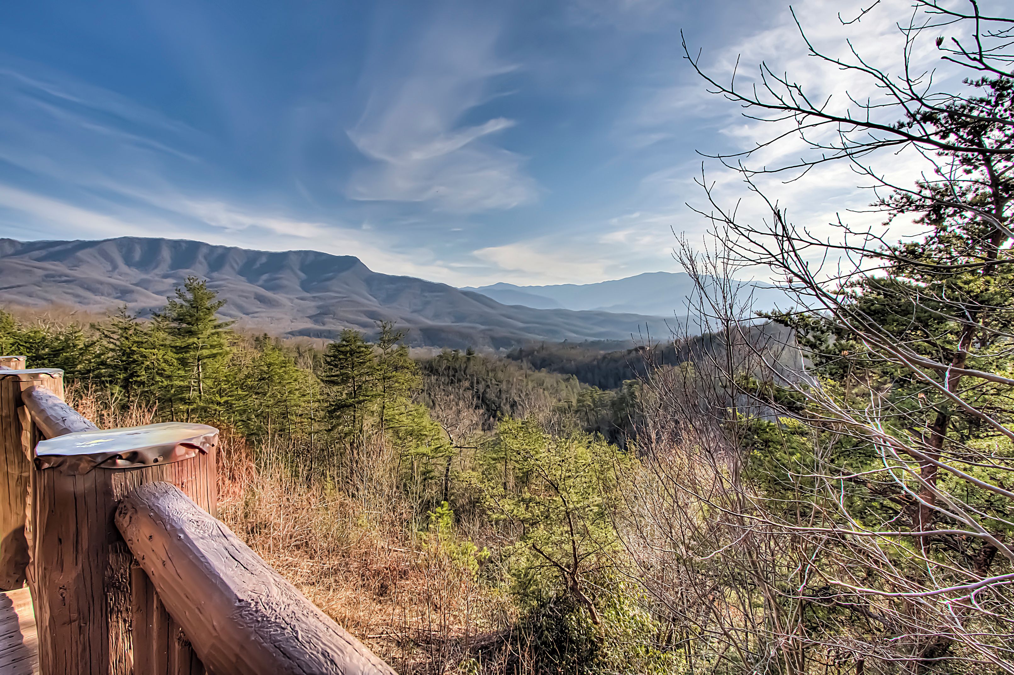 A wooden fence overlooking a mountainous landscape with dense forest and a clear sky.