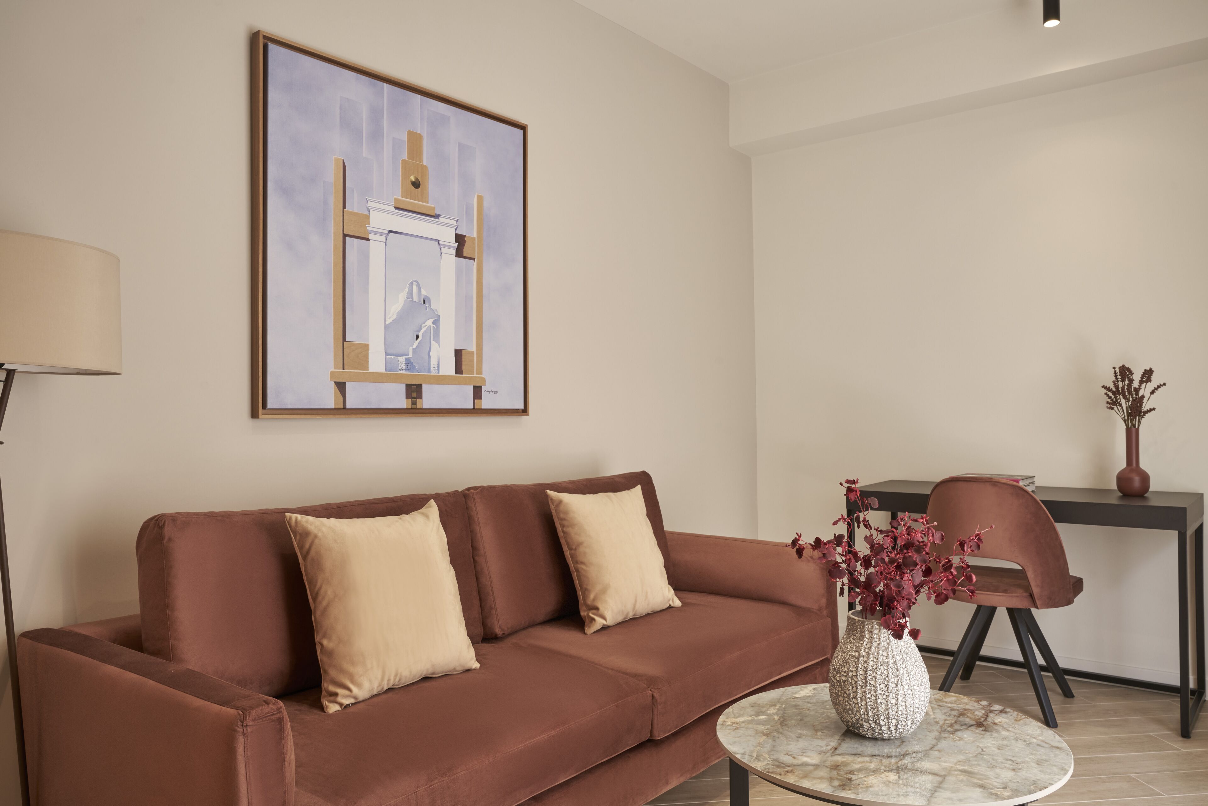 A modern living room with a brown sofa, a round coffee table, and a painting on the wall.