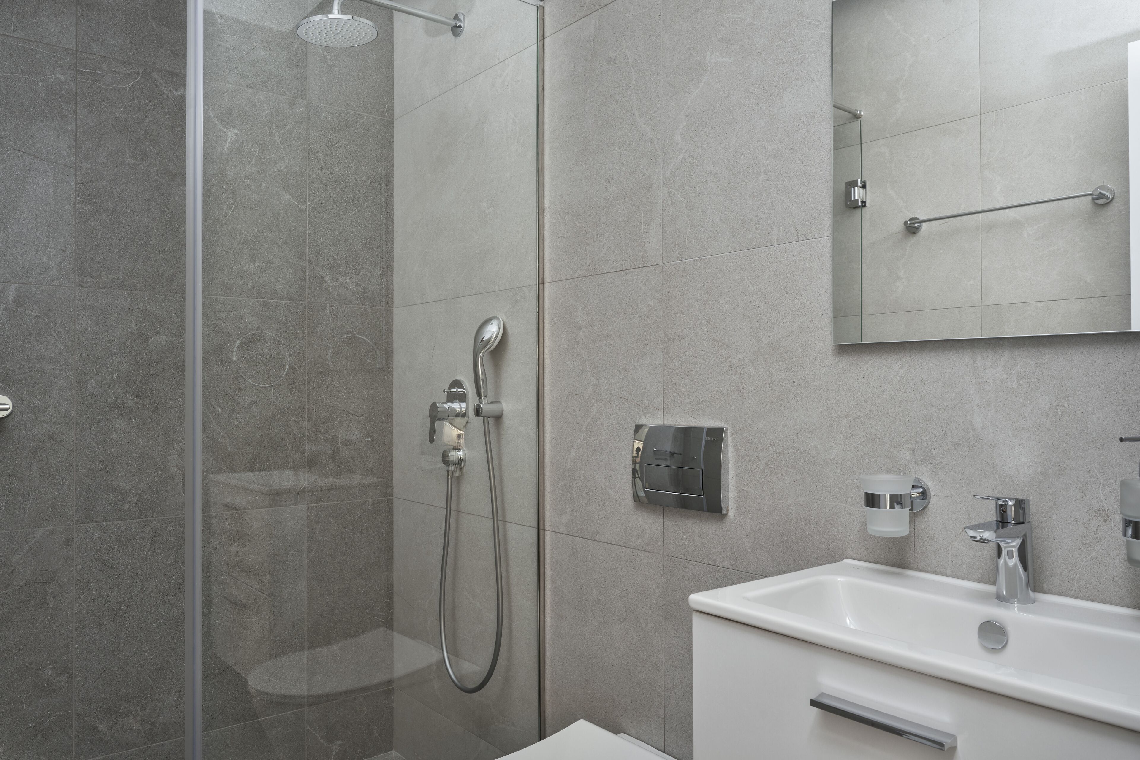 A modern bathroom with a glass-enclosed shower, a white sink, and a mirror.