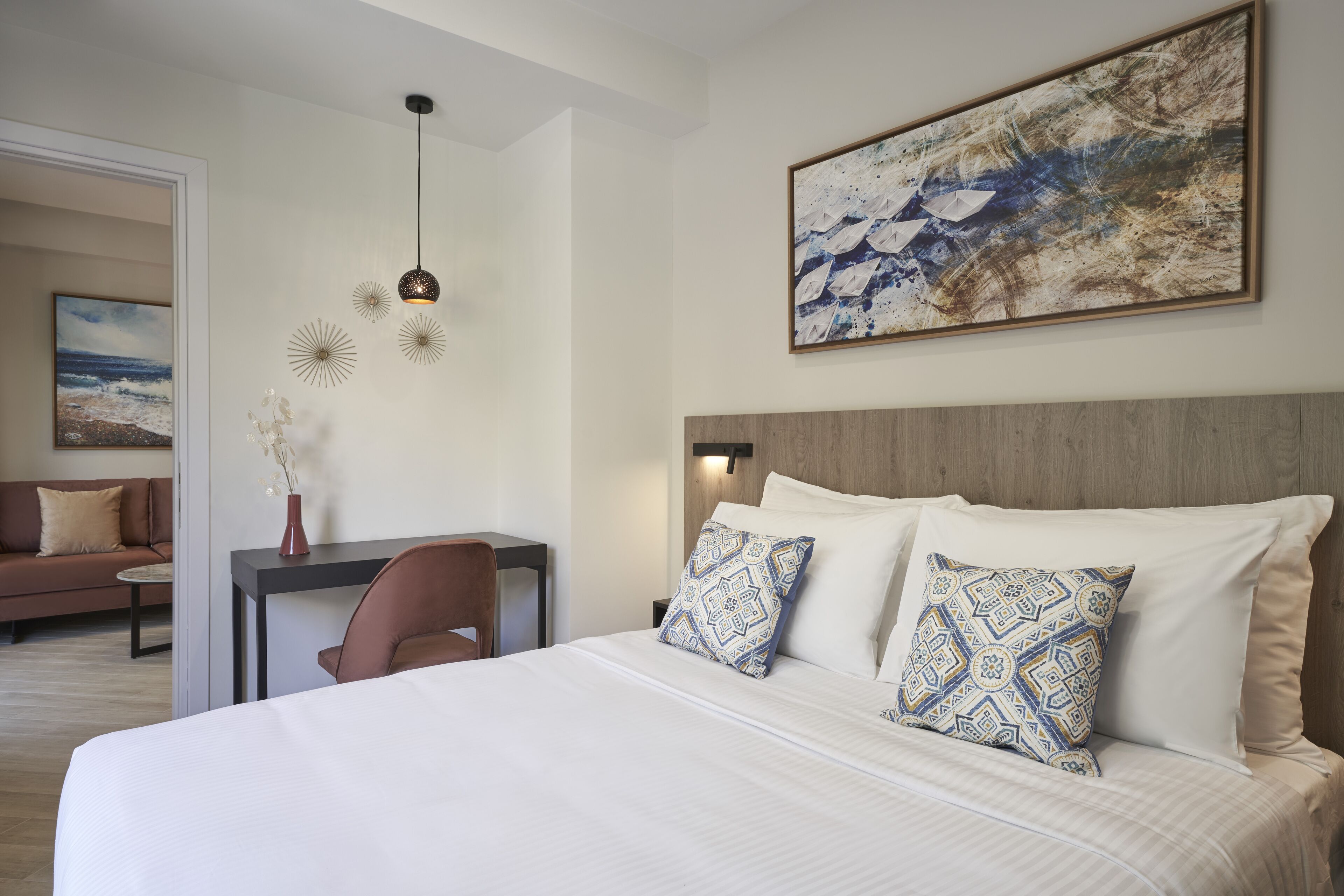 Ein Hotelzimmer mit einem großen Bett, einem Schreibtisch, einem Stuhl und einem Bild an der Wand.