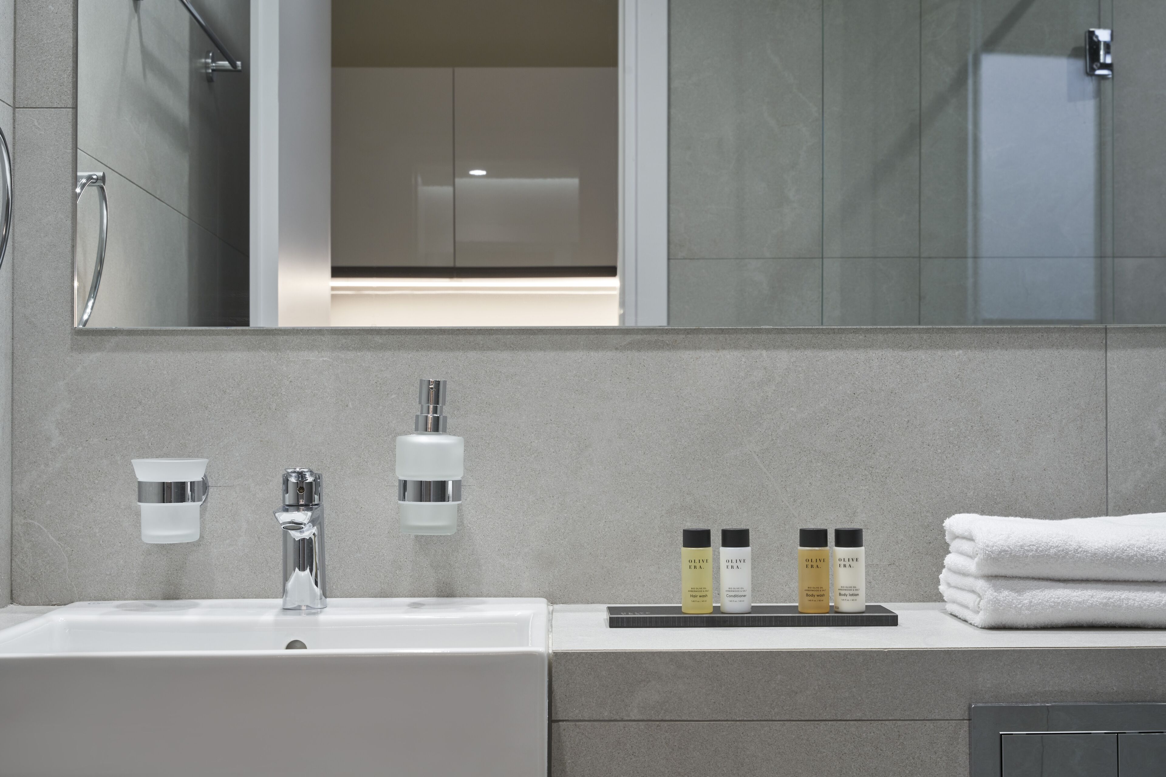 Une salle de bain moderne avec un grand miroir, un lavabo et un porte-serviettes.
