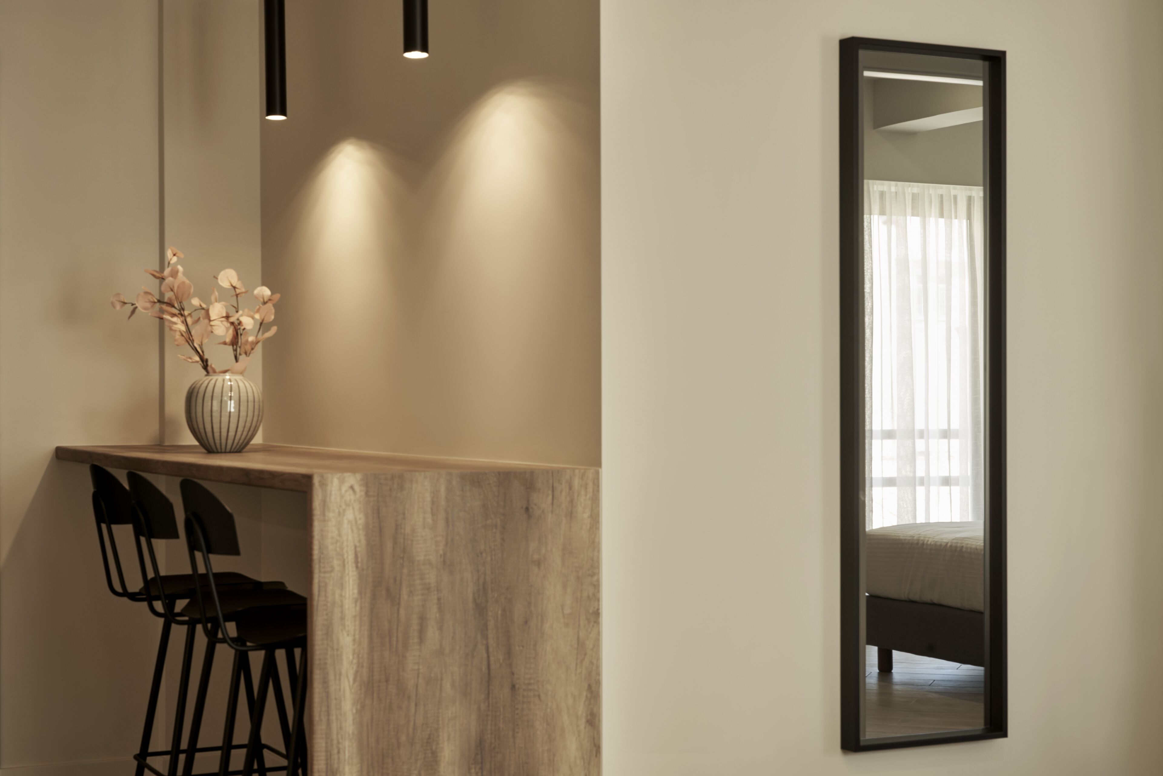 A modern room with a wooden desk, two black chairs, a vase with flowers, a large mirror, and a bed with a white curtain. - Hestia - Asklipiou 61 (Athens)