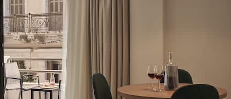 Een eethoek met een ronde tafel, twee stoelen, een fles en twee glazen rode wijn.