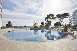 A swimming pool with a clear view of the sea, surrounded by lounge chairs and trees. - Hotel Best Punta Dorada (Salou)