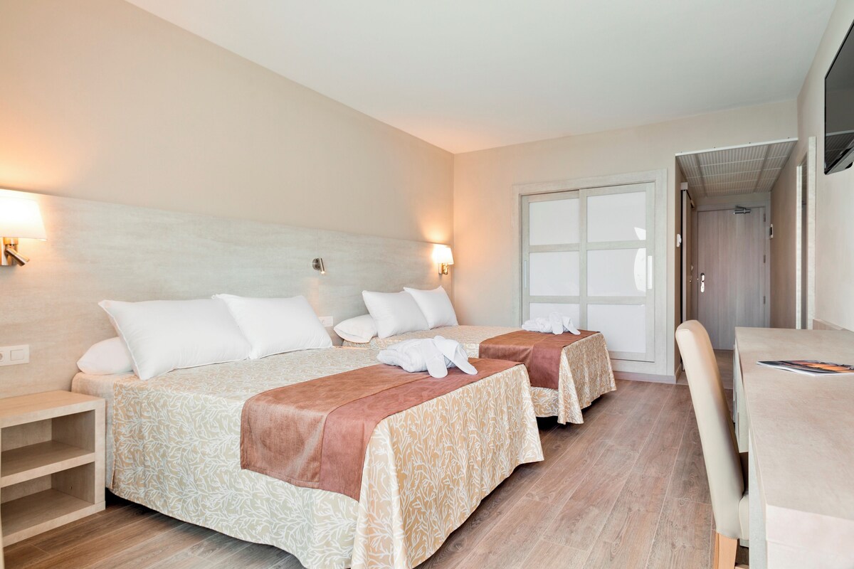 Habitación de hotel con dos camas, un escritorio y una silla.