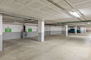 An underground parking garage with concrete pillars, green directional signs, and a parked car. - Hotel Best Punta Dorada (Salou)