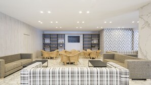 Ein stilvoller Lounge-Bereich mit Sofas, Korbstühlen und einem gemusterten Ottomanen.