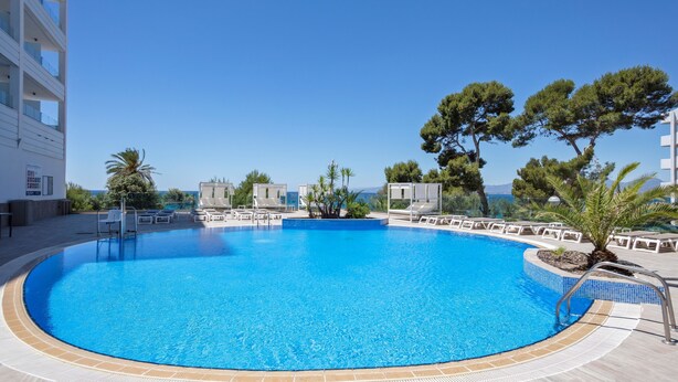 A large, clear blue swimming pool with lounge chairs and a view of the sea. - Hotel Best Punta Dorada (Salou)
