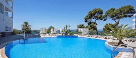 Una piscina al aire libre, sillones reclinables de piscina