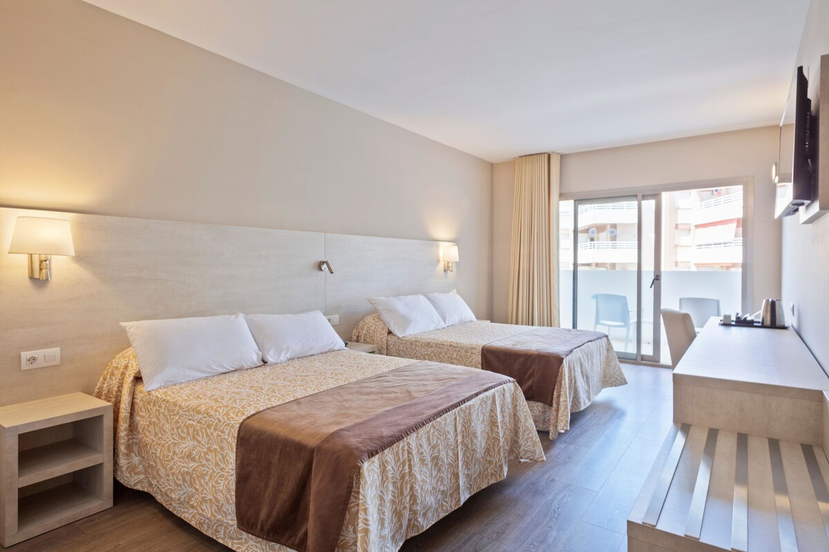 A hotel room with two beds, a desk, and a chair.
