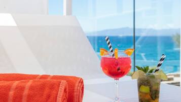Dos bebidas sobre una mesa con una toalla y vista al mar.