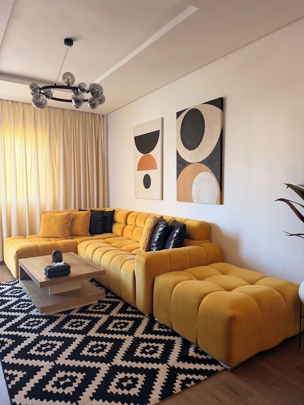 A modern living room with a sectional sofa, a coffee table, abstract wall art, and a patterned rug.