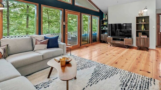 Ein modernes Wohnzimmer mit einer Couch, einem Fernseher und Holzböden.